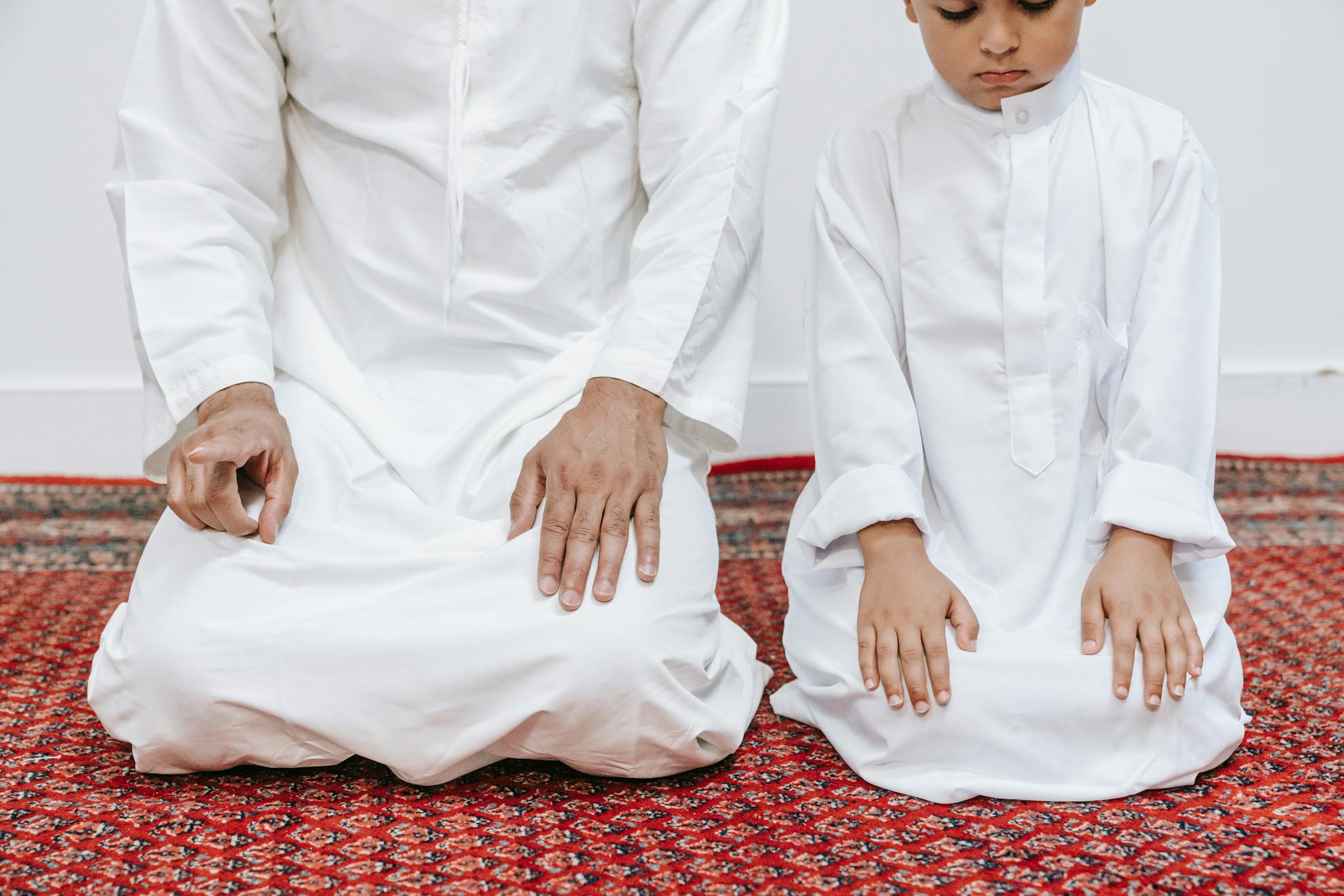 A father and son kneeling in prayer at home, highlighting family and spirituality.