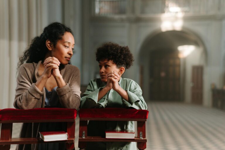 A mother and son praying inside a church, sharing a moment of faith and connection.