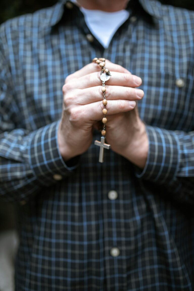Close-up of a man holding rosary beads in prayer. Focus on faith and contemplation.